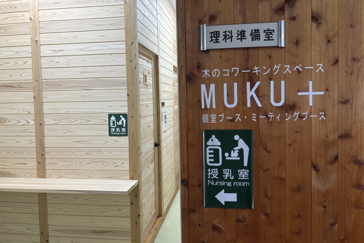 FOREST DOOR 旧神楽小学校2階の授乳室の案内サイン。木の壁に「木のコワーキングスペース MUKU+」と「授乳室 Nursing room」の表示