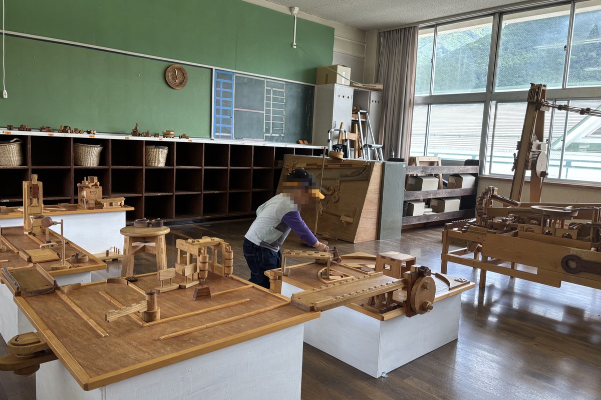 FOREST DOOR 旧神楽小学校の木のおもちゃミュージアム。元教室いっぱいに並ぶ木製の大型ビー玉装置と、奥で遊ぶ3歳の子ども