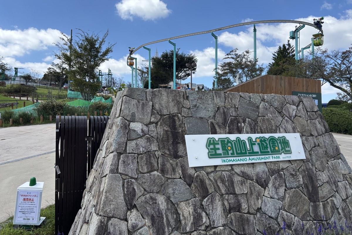 生駒山上遊園地の入口にある石積みのモニュメント。後ろを空中のサイクルモノレールが走る