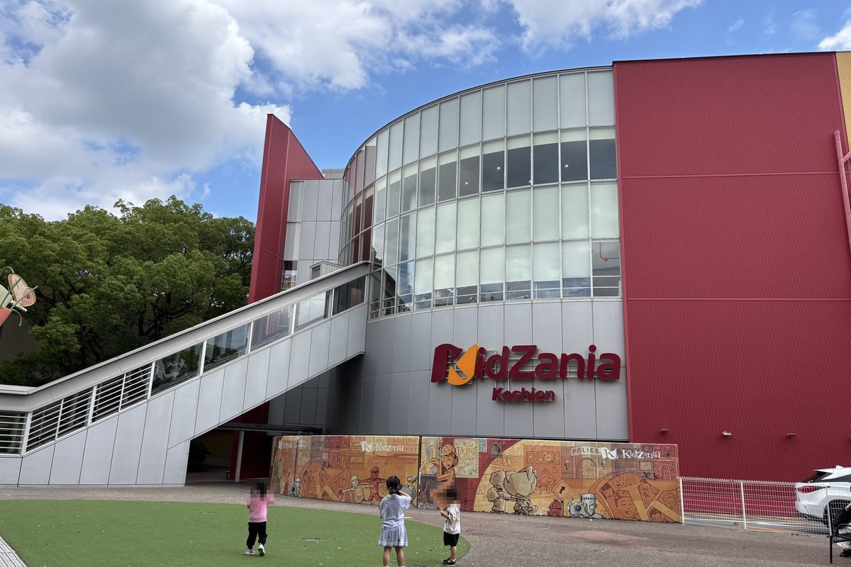 キッザニア甲子園の外観。赤い壁と丸いガラスの建物にKidZania Koshienのロゴ