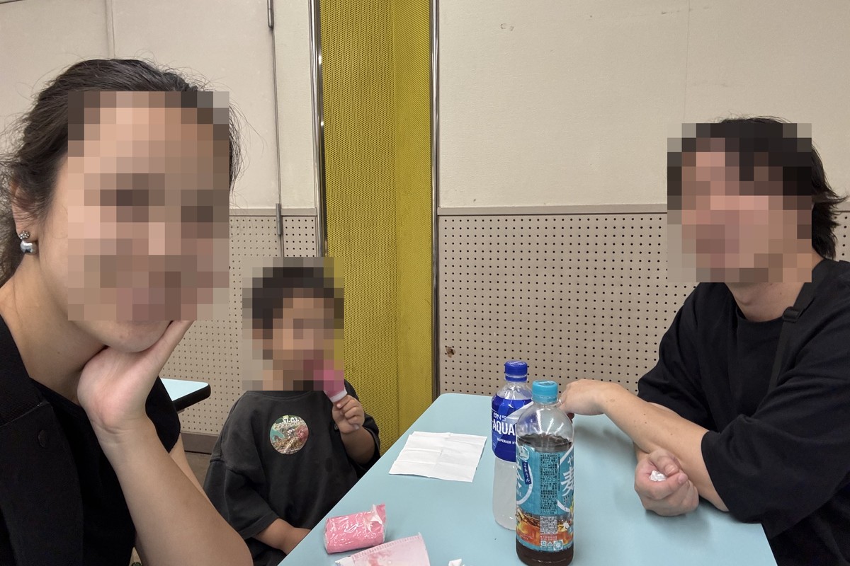 バンドー神戸青少年科学館の北館地下1階の休憩室で、テーブルに飲み物を置いてひと休みする家族3人