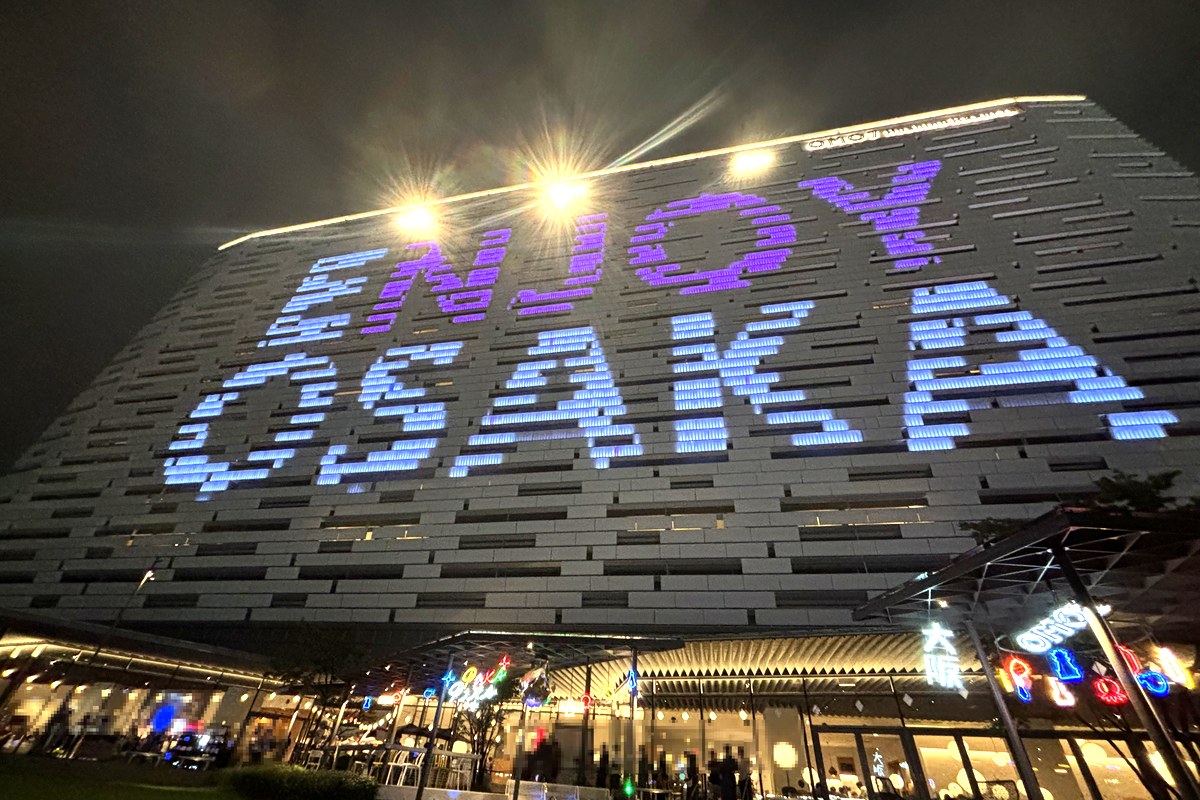 夜のOMO7大阪の外観。建物の壁一面に「ENJOY OSAKA」の光の文字が浮かぶ