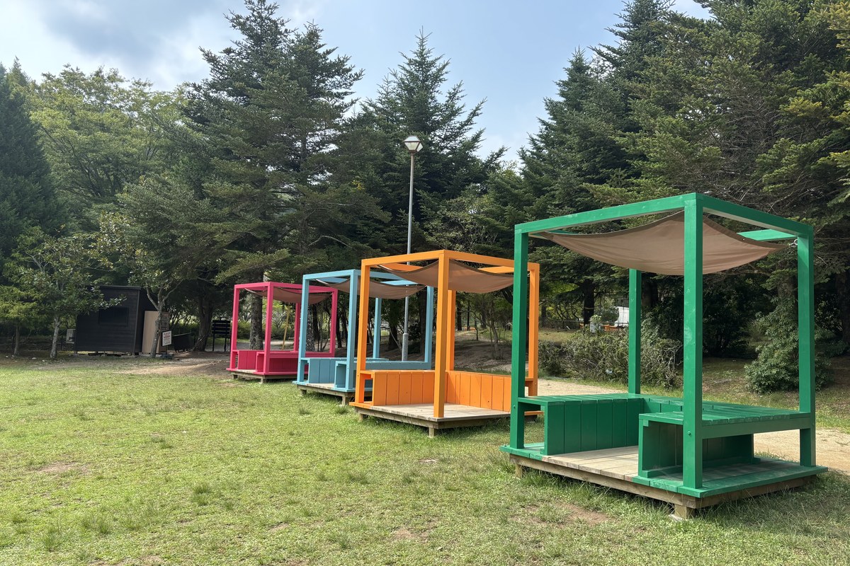 芝生広場に並ぶカラフルな屋根つき休憩スペース