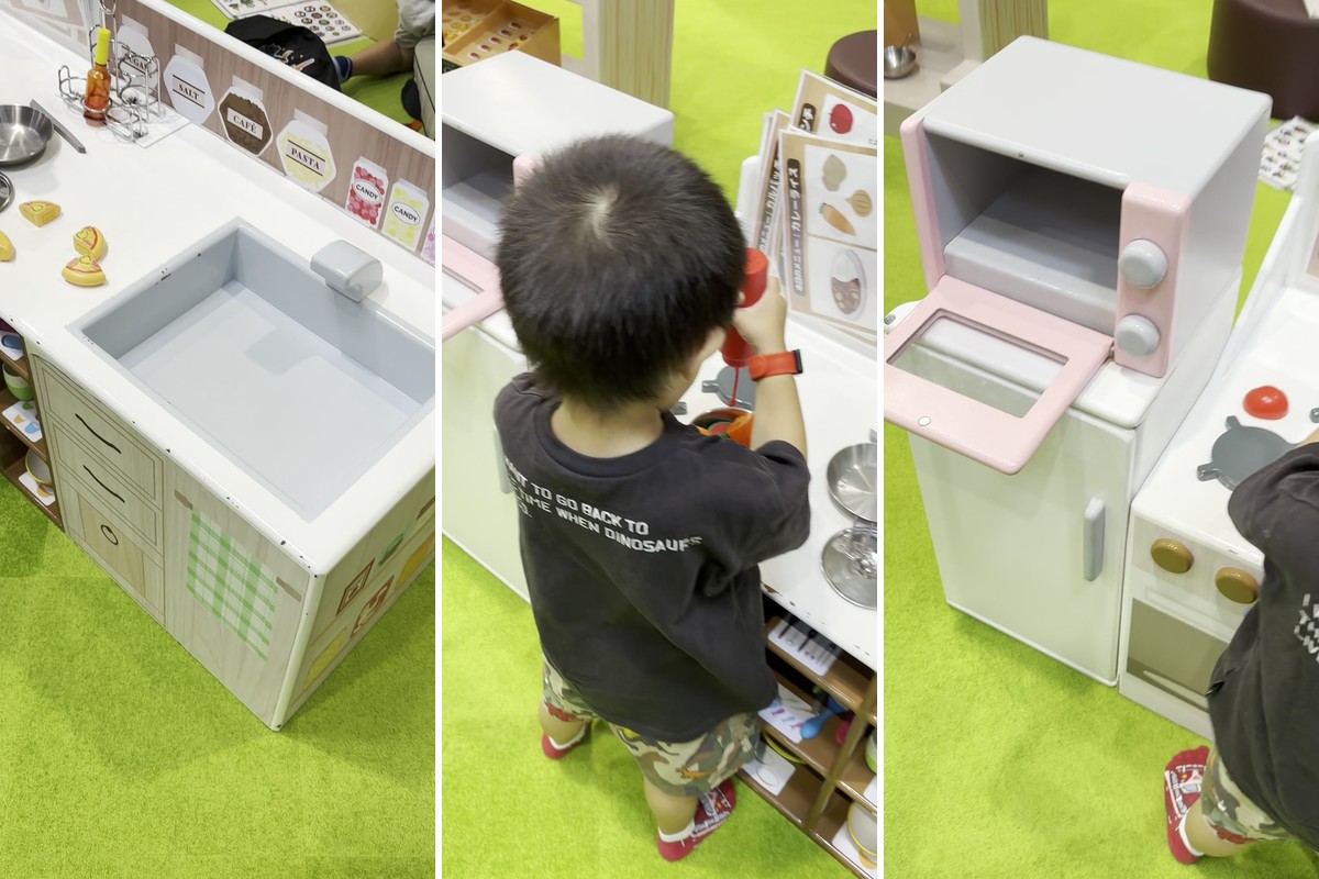 おままごとのキッチン。シンクとコンロのある白いキッチン、調味料のおもちゃで料理する子どもの後ろ姿、ピンクのオーブントースター