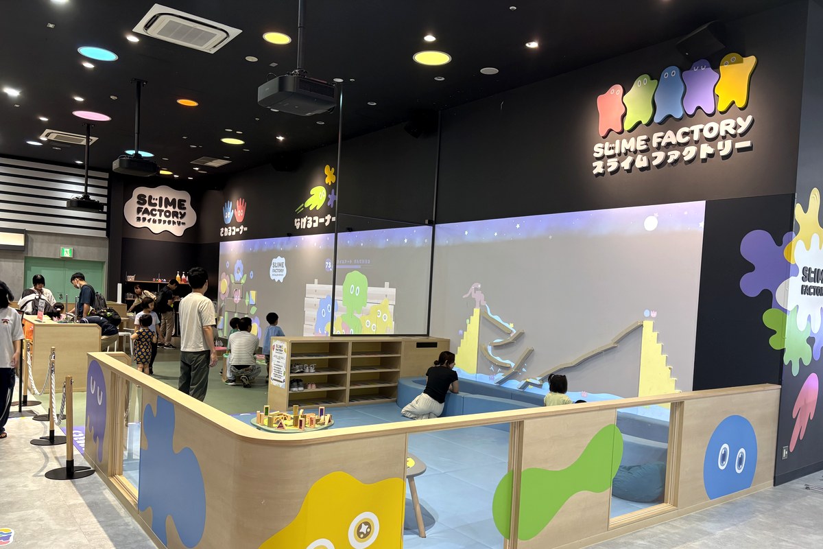 スライムファクトリー（イオンモール神戸北）の全景。SLIME FACTORYの看板の下に、投げる壁・すべり台・ボールプールが見えるガラス張りのエリア