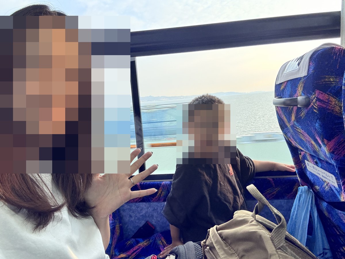 関西空港へ向かうリムジンバスの車内で海を眺める3歳児と母
