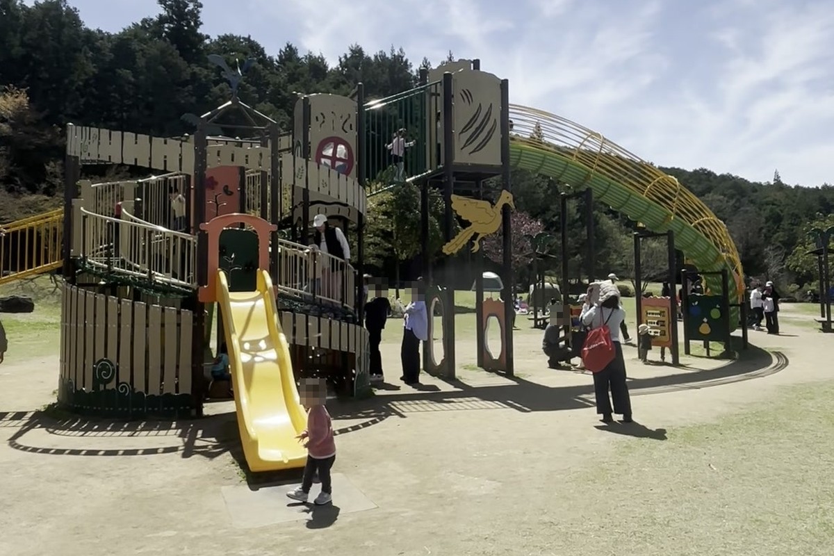 丹波並木道中央公園の大型複合遊具。黄色いすべり台へ走っていく子どもと、奥へ長く伸びる緑色のチューブ状の遊具