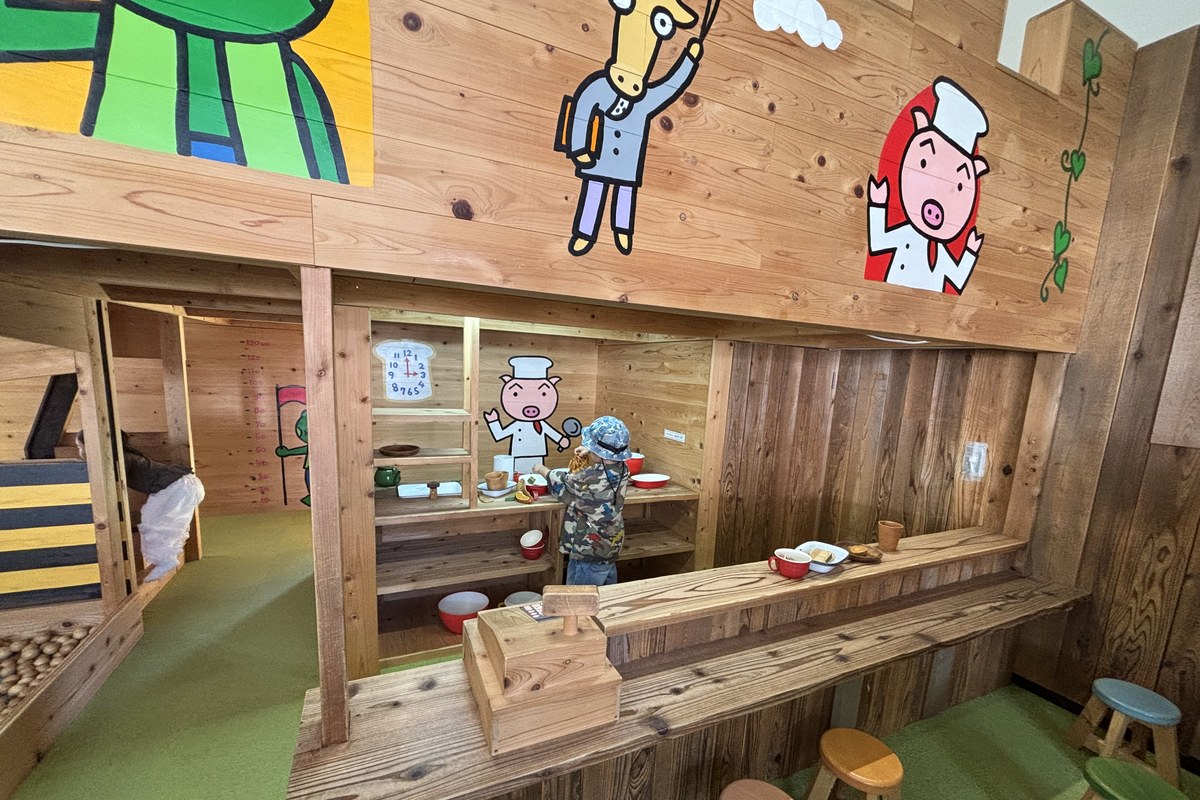 ちるみゅー城のおままごとカフェ。コックさんの絵の木のカウンターとお皿のおもちゃ、カウンターの外の丸いす