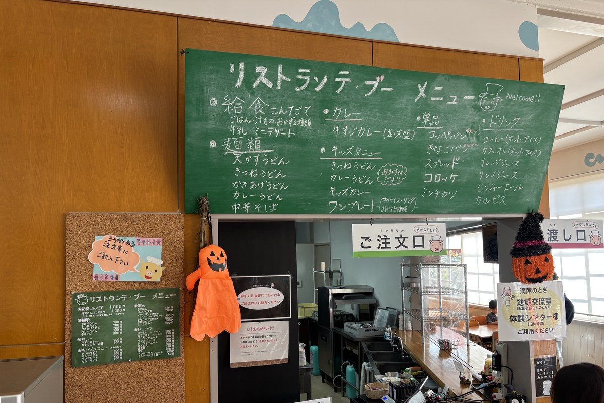 食堂リストランテ・ブーの注文口と黒板メニュー。給食こんだて1,000円、うどん700円、キッズメニュー500円から