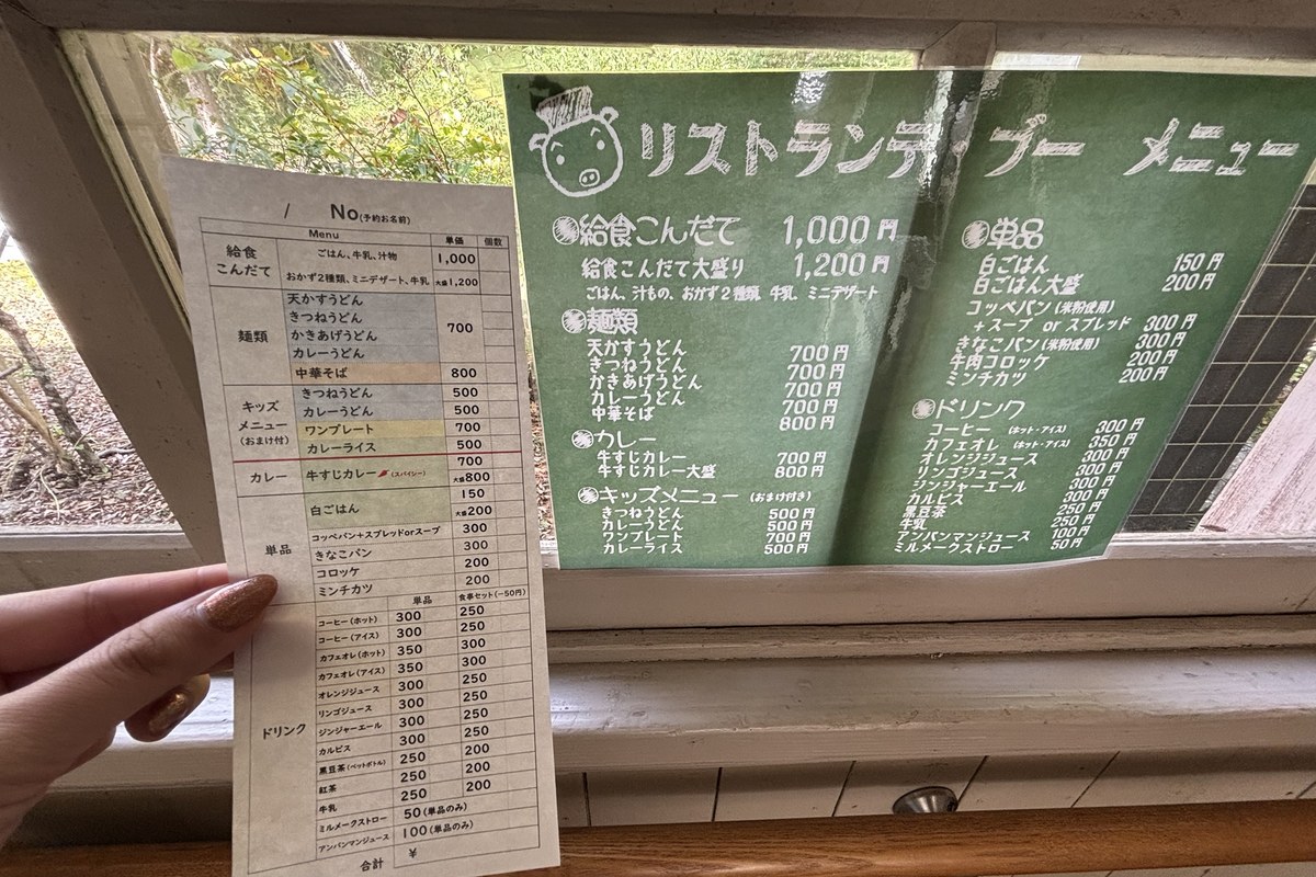 食堂のオーダー用紙と黒板メニュー。給食こんだて1,000円、麺類700円、キッズメニュー500円からの価格が並ぶ