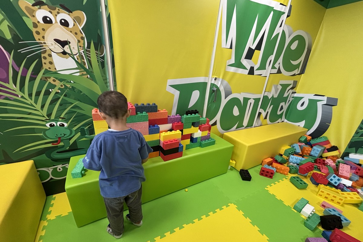 ブロックコーナーで大きなブロックを積む4歳の息子の後ろ姿。壁にはThe Partyの文字