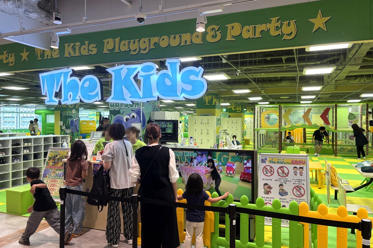 ザキッズ 神戸ROKKO i PARK店の入口。青い「The Kids」の看板の下に受付と靴箱があり、奥に黄緑のプレイエリアが広がる