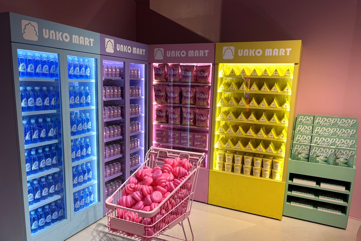 うんこのお菓子や飲み物が並ぶ冷蔵ケースと、うんこが山盛りのショッピングカートがあるフォトスポット「UNKO MART」